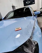 Aplicación de film protector de pintura sobre el capó de un vehículo durante el proceso de instalación.