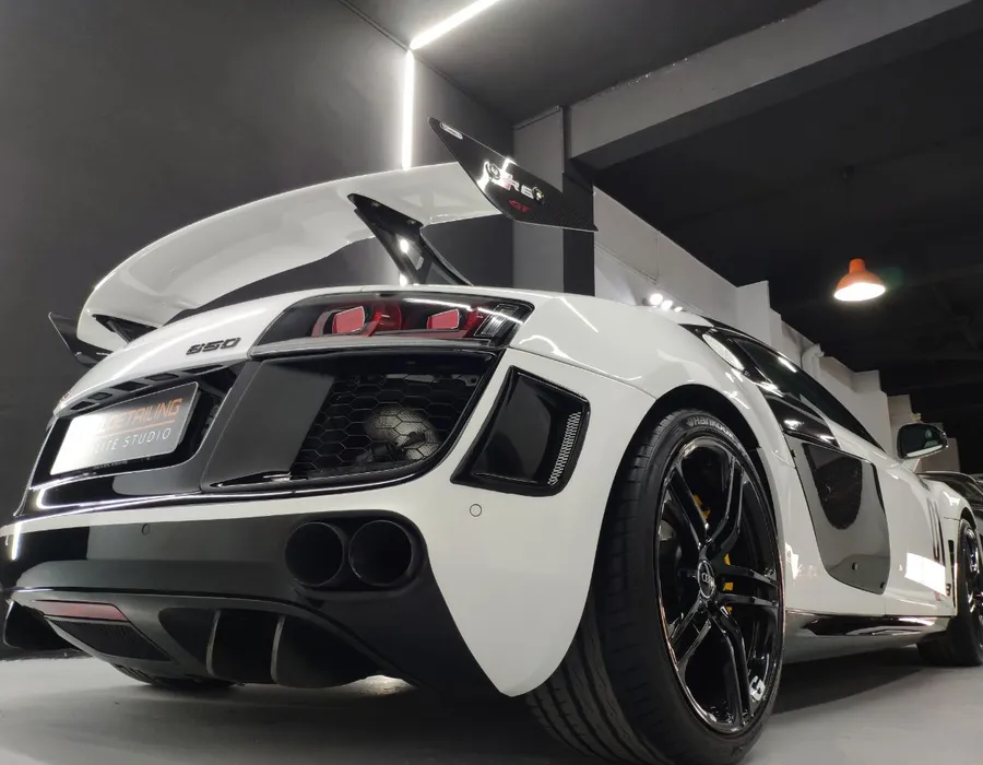 Audi R8 blanco visto desde atrás con el alerón levantado, mostrando el acabado de la pintura tratada.