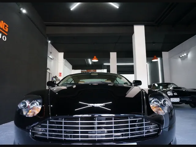 Frontal de un Aston Martin negro fotografiado en el estudio, con el rótulo de Model Detailing al fondo.
