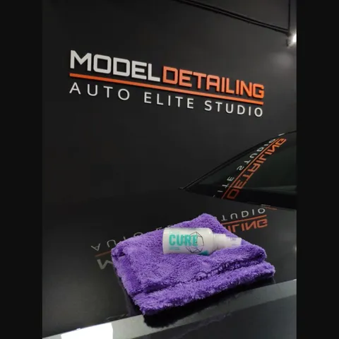Bote de producto cerámico sobre el capó de un vehículo, con el rótulo de Model Detailing al fondo.
