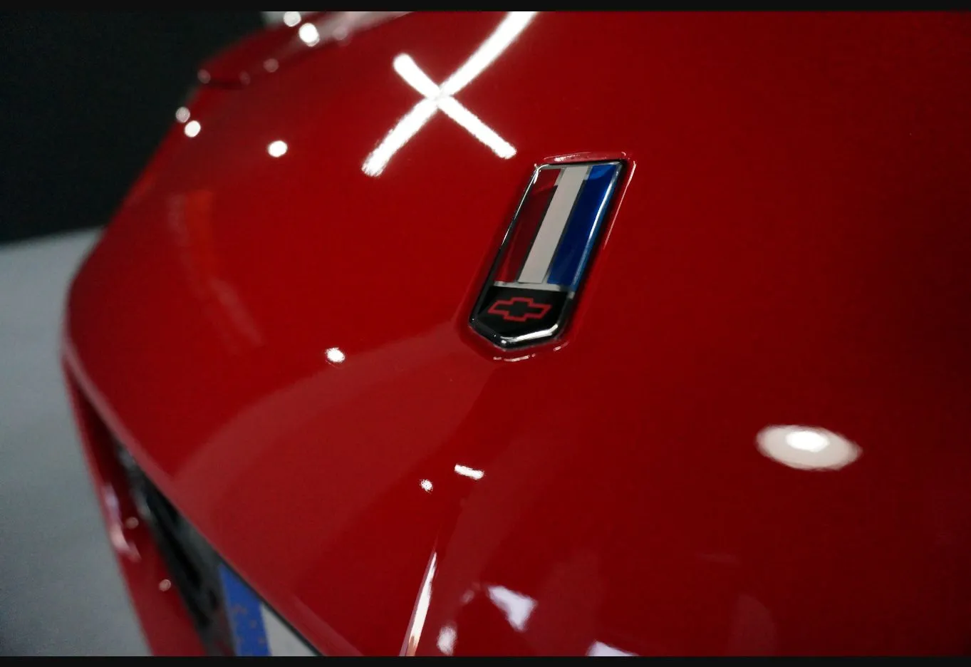 Detalle macro de una carrocería roja con reflejo de luz cruzado, mostrando la profundidad y el brillo de la pintura.