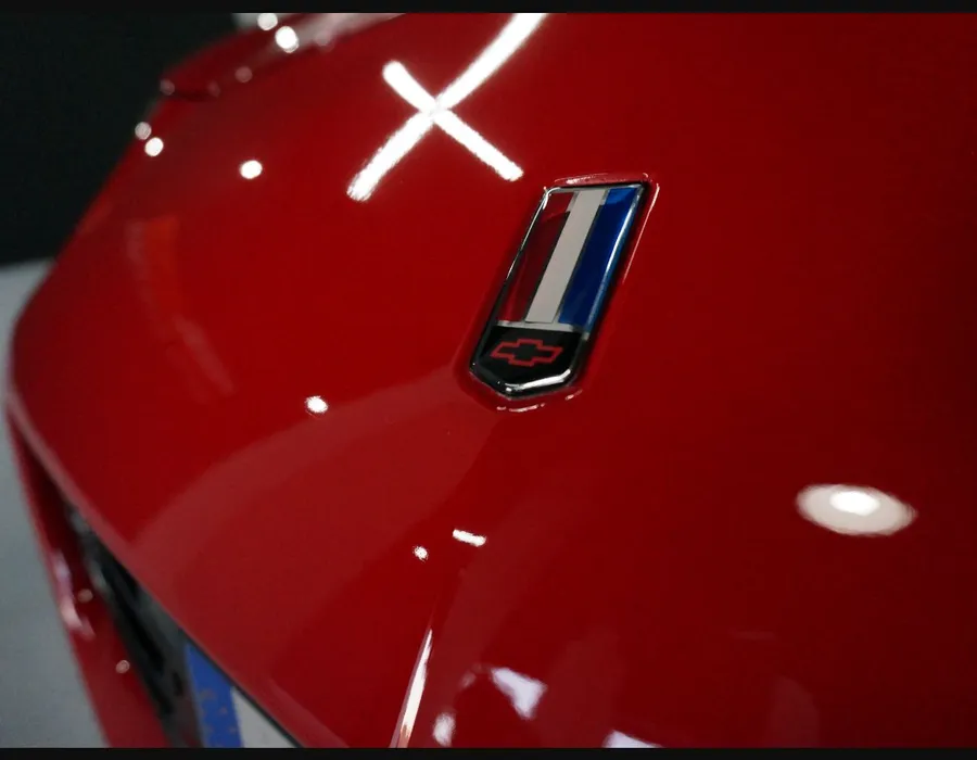 Macrofotografía de pintura roja pulida con un marcado reflejo de luz.