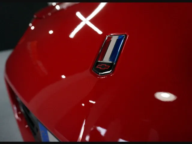 Macrofotografía de pintura roja brillante con un reflejo de luz en forma de cruz sobre la superficie.