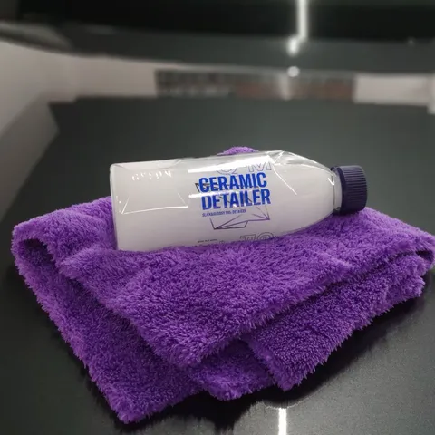 Bote de detailer cerámico de mantenimiento sobre un paño de microfibra en el estudio.